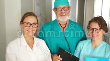 三个穿着医用长袍和眼镜的医生正微笑着看着相机。 国际医生日